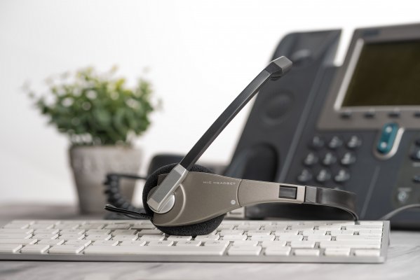 voip service voip phone headset on computer keyboard flower pot in the background